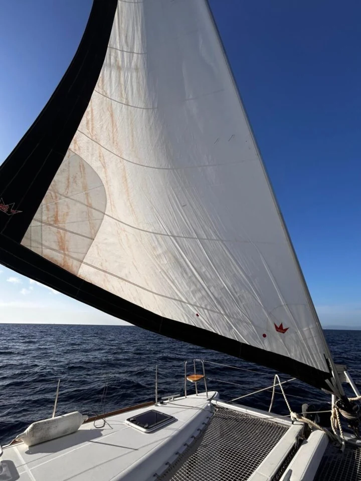Vela de proa e convés de um catamarã durante a navegação.